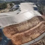 Lahan bekas tambang dengan lereng bertingkat dan area reklamasi untuk pengendalian erosi